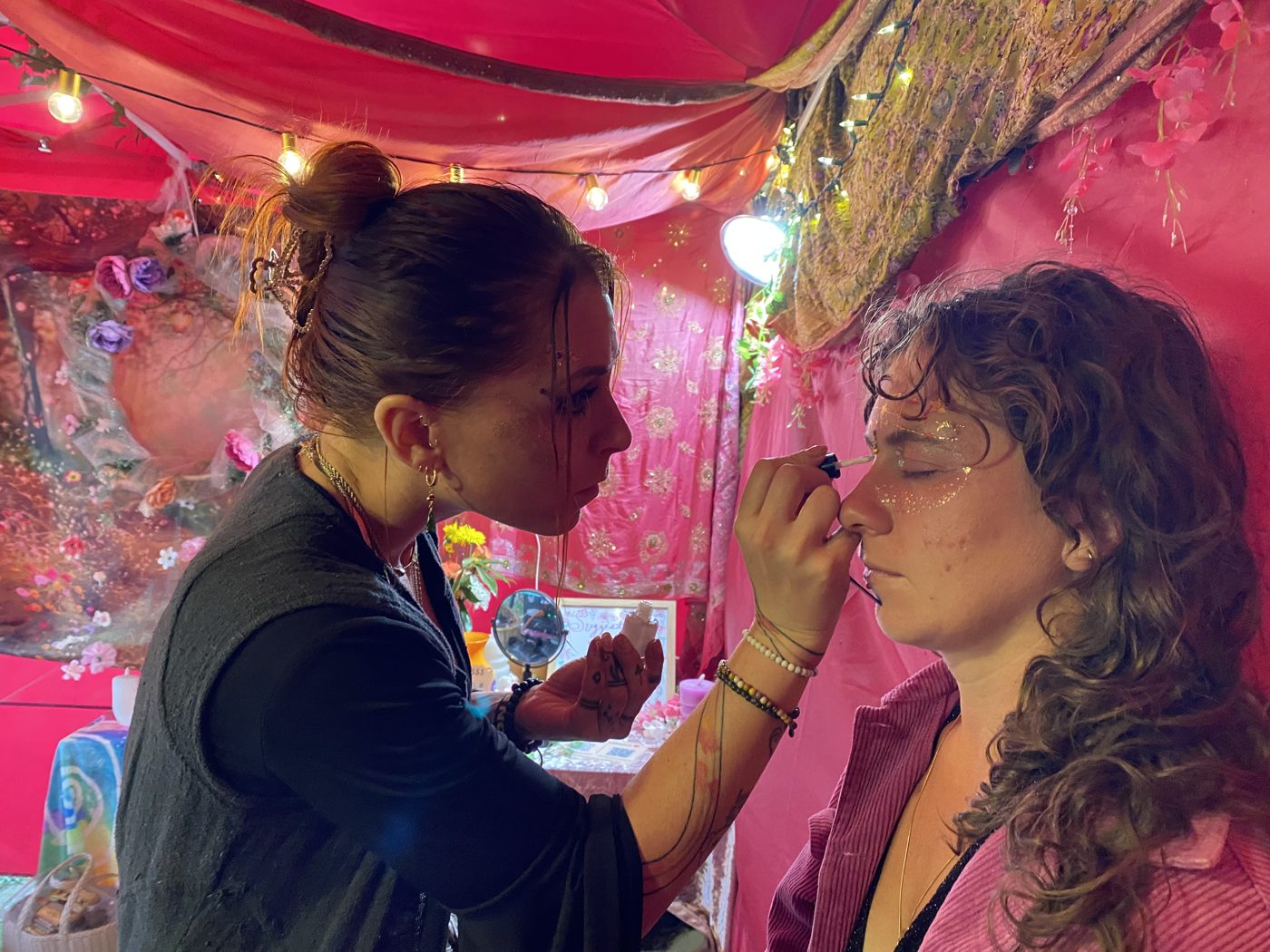 Shiffy painting a guest at a festival booth